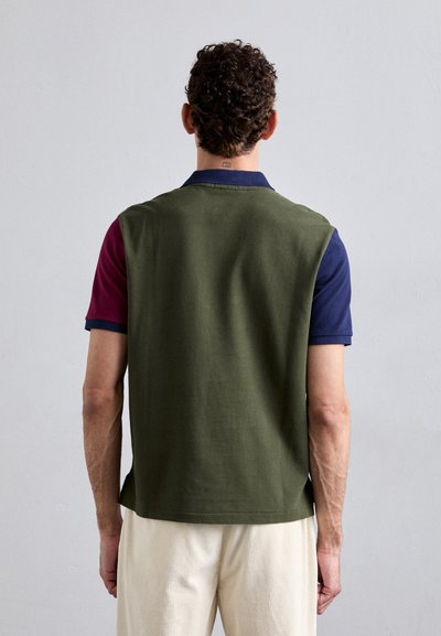 Poloshirt met een groene achterkant, korte maroon en marineblauwe mouwen, gestructureerde stof en een klassieke kraag. Minimalistisch ontwerp met zijsplitten.