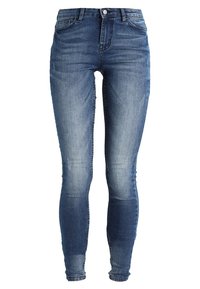 Jeans ajustados en denim azul medio con un acabado desgastado. Presentan un cierre de botón y cremallera, cinco bolsillos y un ajuste ceñido por las piernas.