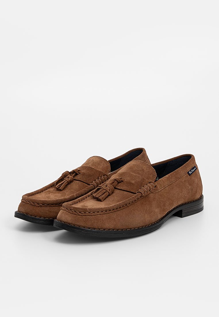 Braune Wildleder-slipper mit Mokassinschnitt, ausgestattet mit einem Quastenakzent, gestickten Details und einer schwarzen Gummisohle.