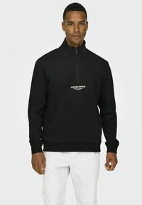 Black quarter-zip sweatshirt made of cotton blend fabric, featuring a ribbed hem, cuffs, and white printed logo on the chest.