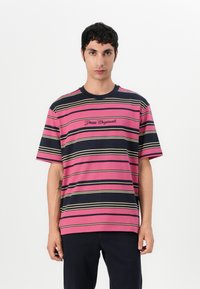 Rožinė ir tamsiai mėlyna trumpomis rankovėmis dryžuota marškinėliai su išsiuvinėtu užrašu "Guess Originals" krūtinėje. Pagaminta iš medvilnės, laisvas kirpimas, apvalus iškirpimas.