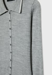 Cardigan gris à manches longues en maille côtelée avec col et boutons noirs sur le devant.