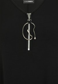 Schwarzes Oberteil aus glattem Stoff mit einem Reißverschluss vorne und einem silbernen Ziehgriff, akzentuiert durch ein einzigartiges Schlaufen-Detail neben dem Reißverschluss.