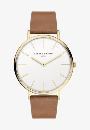 Rund ur med hvid urskive, guldfarvet metalhus og brun læderrem. Udviklet med minimalistiske timemarkører og logoet "LIEBESKIND BERLIN."