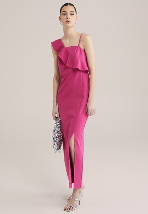 Fuchsia sleeveless dress with ruffle detail, side slit, and form-fitting design. Paired with metallic heels and a silver fringed clutch.
