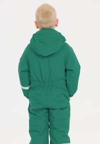 Grøn vandtæt overall med hætte, elastisk talje og reflekterende hvide accenter. Glat tekstur, designet til udendørs aktiviteter.