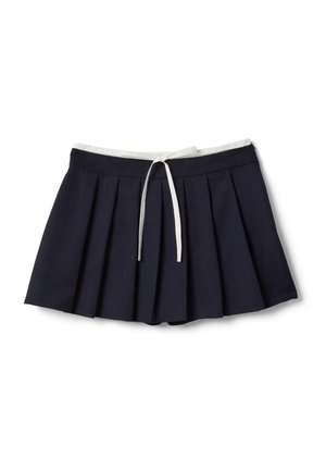 Gonna da tennis plissettata blu navy con fascia in vita bianca e coulisse bianca sul davanti, vista dall'alto su sfondo bianco.