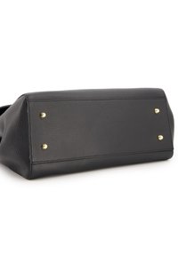 Base de sac à main en cuir noir avec une surface texturée, une forme angulaire et des pieds en métal doré pour plus de soutien.