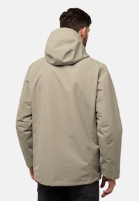 Giacca impermeabile beige con cappuccio, dal fit rilassato e dettagli delle cuciture. Texture liscia e design minimalista.