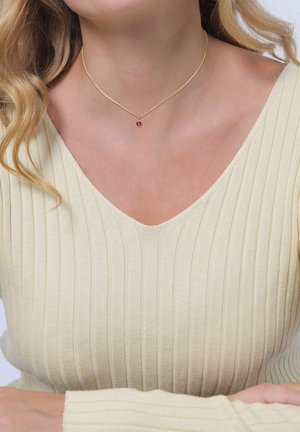 Goldene Halskette mit einem kleinen rosa Edelstein in der Mitte, getragen über einem hellbeigen, gerippten Oberteil mit V-Ausschnitt.
