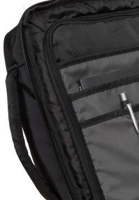 Intérieur d'un sac en nylon noir avec une doublure grise lisse. Comprend plusieurs poches, un stylo et une fermeture à glissière. Tissu texturé avec des bords renforcés.