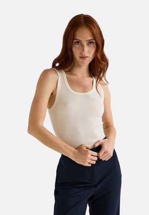 Débardeur côtelé en écru avec un col rond large et une coupe ajustée, associé à un pantalon rayé bleu marine.