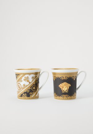 Keramikbecher mit kunstvollen goldenen und schwarzen Mustern. Einer zeigt ein wirbelndes Design, der andere ein Medusa-Motiv. Beide haben gebogene Griffe.