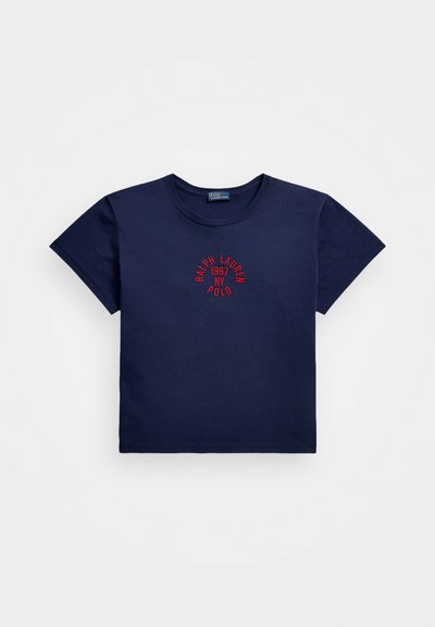 Tumši zils kokvilnas T-krekls ar īsām piedurknēm, centrā ar sarkanu izšūtu logo, kas lasāms "RALPH LAUREN 1967 NY POLO".