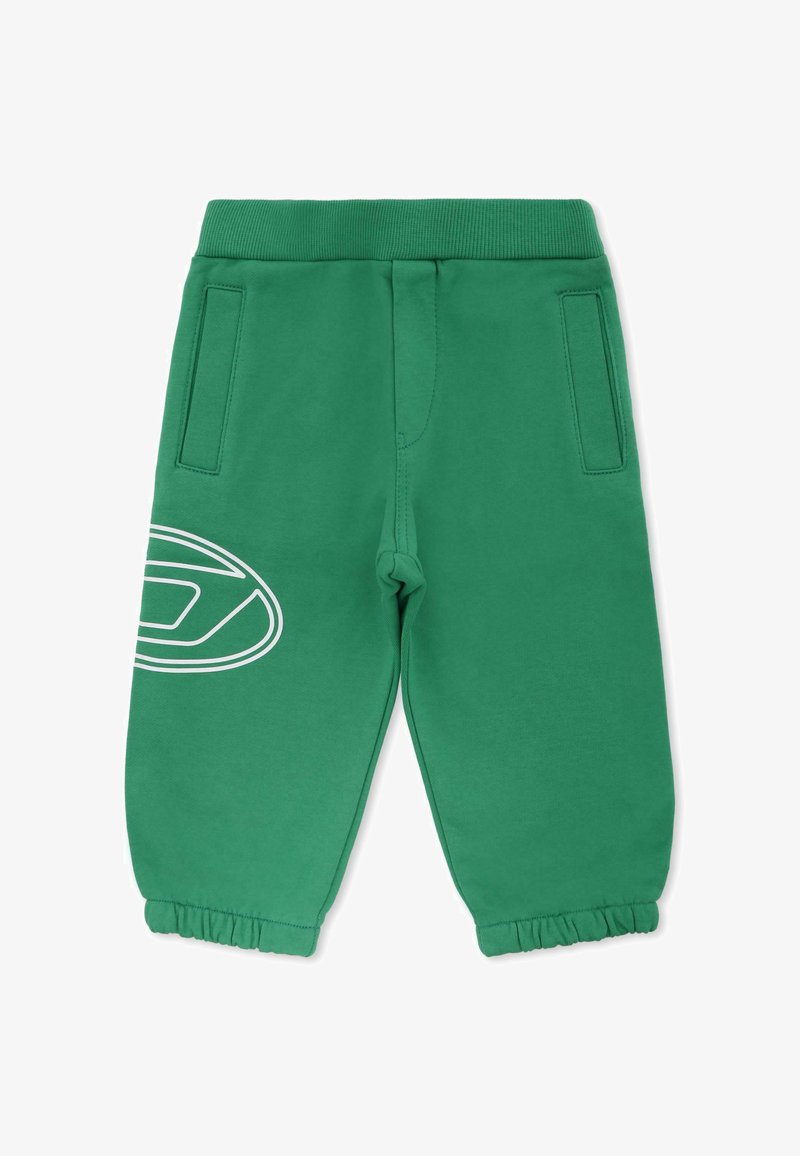 Groene joggingsbroek van zacht materiaal, met een elastische tailleband, zijzakken en een witte cirkelvormige grafiek op het linkervak.