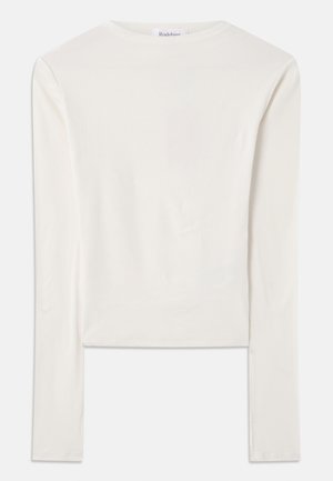 Haut à manches longues blanc en coton, dotée d'un col ras du cou simple et d'une coupe ajustée. Le tissu est lisse avec une légère élasticité.
