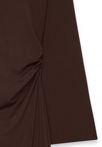 Maglia a maniche lunghe marrone realizzata in tessuto morbido, con dettagli arricciati sui lati e un design leggermente drappeggiato.