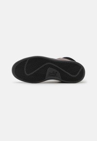Fekete gumitalpú sneaker, híg mintázattal, textúrált felülettel és a márka logójával a side-on.