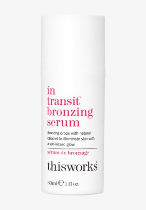 Hvid cylindrisk flaske med pumpetop, mærket "in transit bronzing serum" i pink tekst. Indeholder 30 ml produkt til hudoplysning.