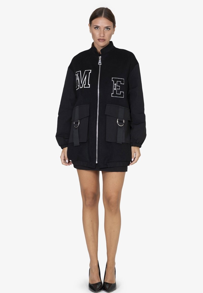 Zwarte bomberjack met ritssluiting, oversized ontwerp, grote voorzakken, geborduurde letters "M" en "E", gestructureerde stof en elastische zoom.