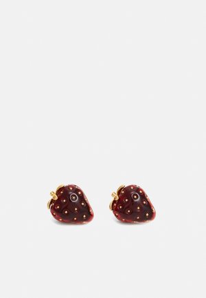 Paire de petites boucles d'oreilles rouges en forme de fraise avec des graines et des feuilles dorées sur fond blanc.