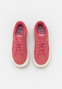 Baskets en daim rose avec semelles en caoutchouc blanc, dotées d'un design à lacets et d'une semelle intérieure texturée à motif. Marquage doré sur le côté.