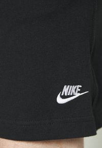 Black athletic shorts made of smooth cotton, featuring a white embroidered Nike logo on the lower left side and a simple hem finish.