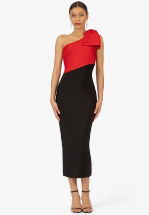 Een one-shoulder jurk met een rode top met een strik en een zwarte, aansluitende rok. Gemaakt van een gladde stof met een aansluitende snit.