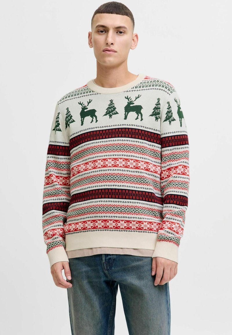 Maglione lavorato a maglia color crema con motivi rossi, verdi e neri che raffigurano renne, alberi e disegni geometrici. Polsini e orlo a costine.