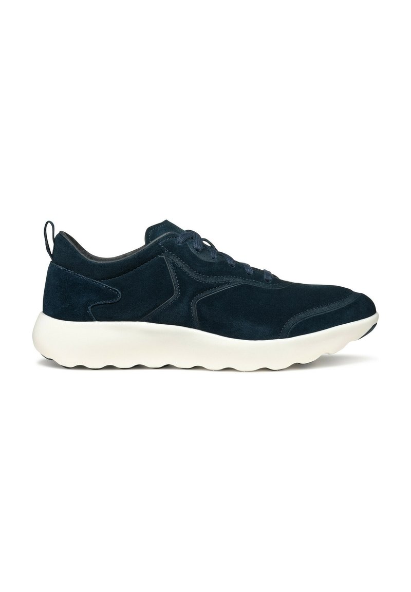 Zapatilla deportiva de ante azul marino con suela blanca y acolchada, punta redondeada y costuras en contraste; cuenta con cierre de cordones y tira trasera.