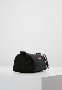 Borsa cilindrica nera realizzata in tessuto testurizzato, con una patch con logo e una chiusura con cordoncino per una conservazione sicura.