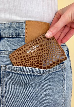 Brown faux leather cardholder featuring a textured crocodile pattern, partially inserted in a back pocket of blue denim jeans.