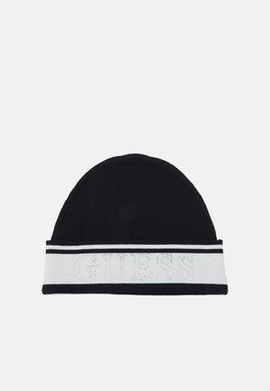 Gorro de punto negro con una banda blanca que presenta la palabra "GUESS" en strass y dos rayas horizontales. Textura suave, diseño de parte superior redondeada.