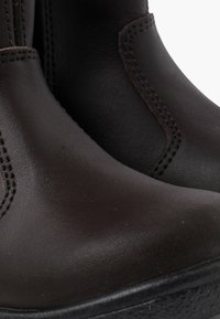 Stivaletti alla caviglia in pelle marrone con una texture liscia, dotati di pannelli laterali elastici, cuciture in contrasto e suola in gomma.