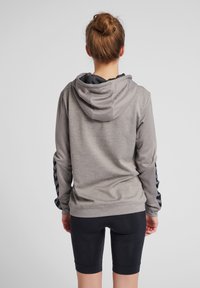 Felpa grigia con tessuto testurizzato e dettagli neri sulle maniche, abbinata a pantaloni corti neri. Caratterizzata da un fit rilassato e cappuccio.