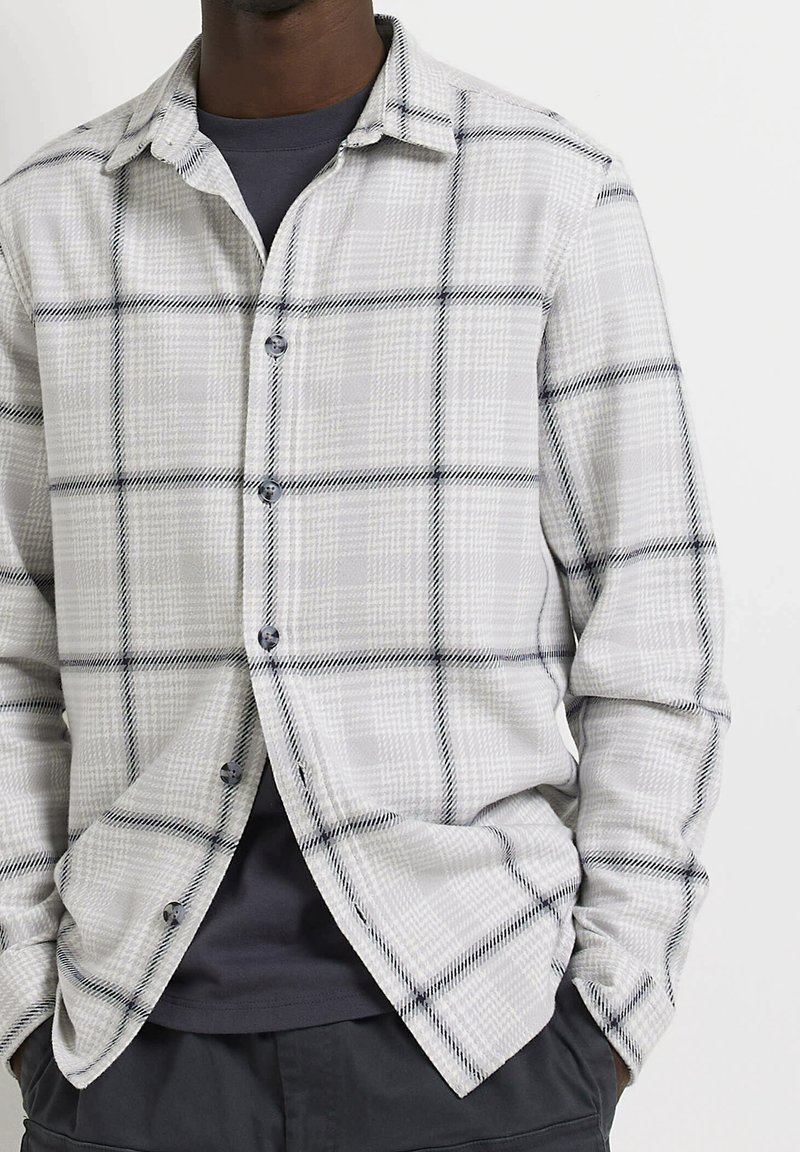 Camicia button-up in un tessuto grigio chiaro con un motivo a quadri bianco e nero, dotata di colletto standard e chiusura frontale con bottoni.