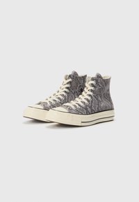 High-top sneakers with a grey snake-print pattern, beige laces, and white rubber soles featuring a textured finish and double black stripes.