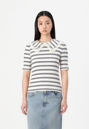 Haut rayé en crème et marine, doté d'un grand col en dentelle et de manches courtes. La texture est côtelée, associé à une jupe en jean.