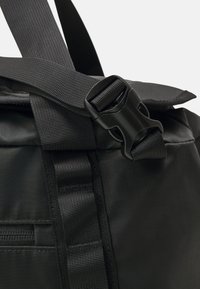 Black fabric bag with webbed strap, featuring a side buckle closure and zipper detail. Material appears smooth with a matte finish.