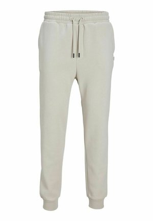 Pantaloni della tuta beige chiaro realizzati in tessuto morbido, con vita elastica e cordino, tasche laterali e polsini a coste.