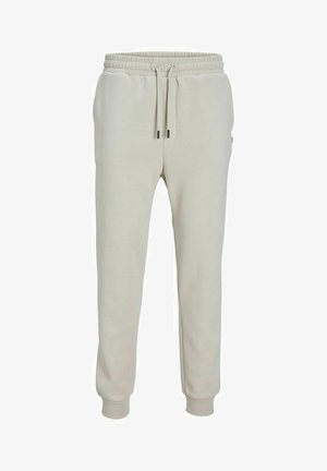 Pantaloni della tuta beige chiaro realizzati in tessuto morbido, con vita elastica e cordino, tasche laterali e polsini a coste.