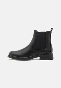 Bottines Chelsea en cuir noir avec des panneaux latéraux élastiques, bout arrondi et un petit talon en bloc. Texture lisse et design minimaliste.