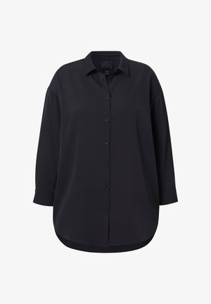 Czarna koszula zapinana na guziki z kołnierzykiem, długimi rękawami i zaokrąglonym dołem. Wykonana z gładkiego materiału, luźna w kroju, bez widocznych wzorów.