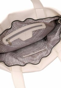 Sac fourre-tout en cuir blanc avec une fermeture éclair en forme de vagues, un extérieur texturé et un intérieur doublé avec des motifs de texte répétitifs en gris.