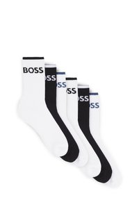 Five pairs of socks in black and white, featuring ribbed cuffs with "BOSS" logo in contrasting colors. Soft cotton blend material.
