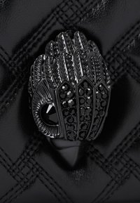 Borsa a mano in pelle nera con superficie testurizzata e motivo trapuntato. Chiusura ornamentale in metallo nero a forma di piume con cristalli.