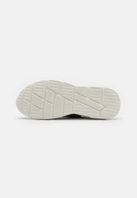 Black athletic shoe sole with a textured white rubber outsole, featuring a grid pattern and grooves for traction.