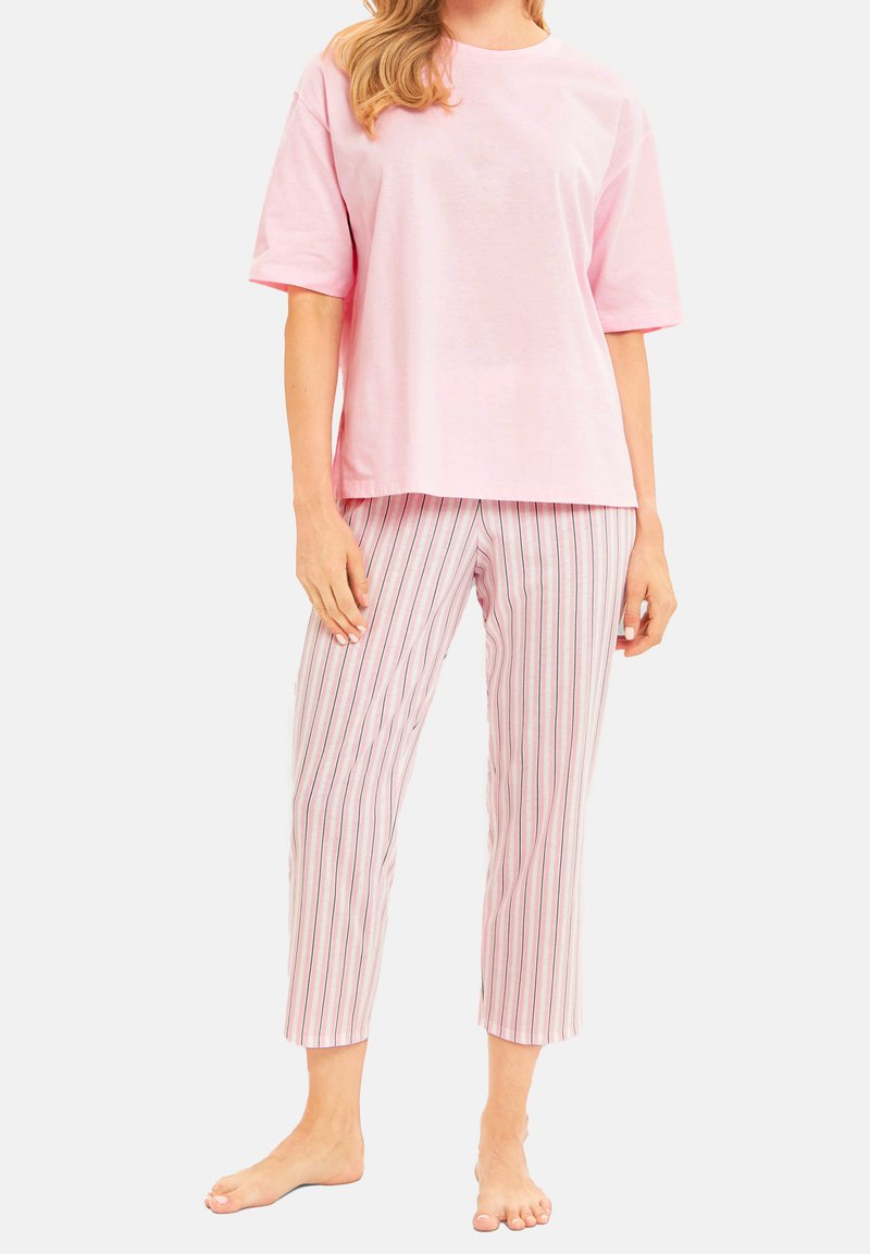 Rosa bomull t-shirt med korta ärmar, matchad med vita byxor som har vertikala rosa, blå och lavendelrandiga mönster.