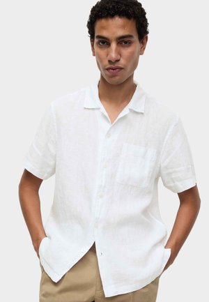 Biała lniana koszula z krótkim rękawem, kieszenią na piersi, zapinana na pojedynczy rząd guzików, o swobodnym kroju.