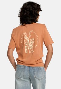 Korte mouwen oranje t-shirt met witte tijgergraphics en tekst op de achterkant. Gemaakt van zachte katoen met een relaxed fit.